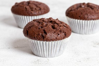 Beyaz kağıt bardaklarda çikolata parçacıkları olan sade çikolatalı kekler, yakın plan görüş, uzay kopyaları.