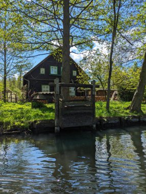 Almanya, Spreewald Biyosfer Rezervi, 27 Nisan 2024: Açık mavi gökyüzünün altında yeşil ağaçların arasına kurulmuş büyüleyici bir kır evi huzurlu bir doğal ortamda sakin bir geri çekilme sunuyor.