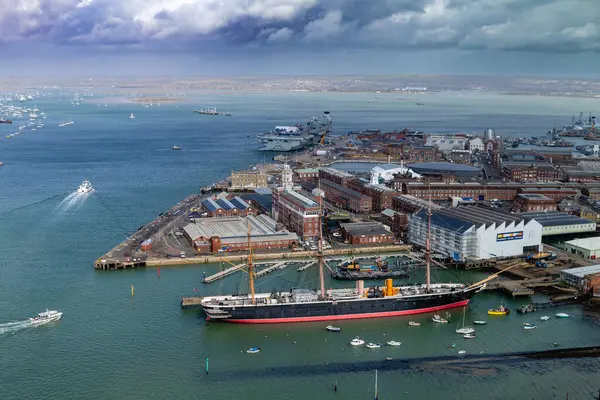 stock image Portsmouth, UK - April 4, 2024: The iconic HMS Warrior, a preserved naval ship, stands out in Portsmouth Harbor against a backdrop of storm clouds and a dynamic cityscape.