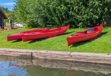 Almanya, Brandenburg, Schlepzig - 16 Ağustos 2024: Sahilde, Schlepzig 'in doğal ortamında kürek çekmeye hazır ahşap bir rıhtımın yanında birçok kano mevcuttur..