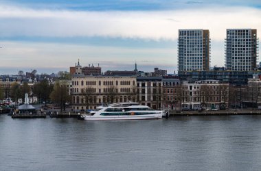 Rotterdam, Hollanda - 1 Nisan 2024: Gösterişli tekne Amalia 'yı sakin bir nehir boyunca tarihi ve modern binaların önüne yanaştırdı..