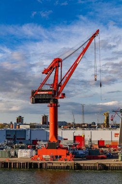 Rotterdam, Hollanda - 1 Nisan 2024: Rotterdams limanı yakınlarındaki ikonik yuvarlak bina, yüksek kırmızı vinçler ve liman tesisleri ile modern mimari ve endüstriyel güç sergilenmektedir..