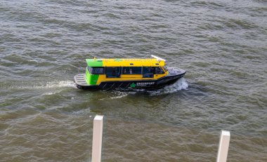 Rotterdam, Netherlands - April 1, 2024: A vibrant Greenport water taxi transports passengers along the Maas River, exemplifying modern city transit in Rotterdams waterways. clipart