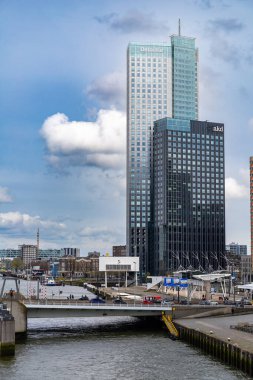 Rotterdam, Netherlands - April 1, 2024: Rotterdams skyline with the Deloitte and AKD towers, set against a partly cloudy sky, overlooking the Maas River. clipart