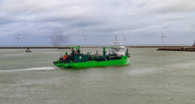 Bruges Belçika - 2 Nisan 2024, geniş açık mavi silindirik petrol tankları kıyı şeridi boyunca bulutlu gökyüzünün altında açık denize bakıyor..