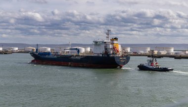 Le Havre, Fransa-3 Nisan 2024 Valletta 'dan gelen siyah ve kırmızı tanker SONGA ATLANTIC liman bölgesindeki yakıt tanklarının yanındaki römorkör tarafından çekiliyor..