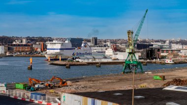 Le Havre, Fransa-3 Nisan 2024, liman ön planında güneş panelleri olan bir SEMT deposu bulunuyor. Arkasında renkli konteynır kemeri ve St. Joseph Kilisesi ile Le Havre silueti yükseliyor..