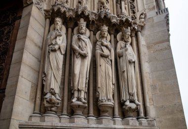 Paris, Fransa-Nisan 16, 2025: Azizlerin ve kralların tam vücut gotik heykelleri katedral kapısının önünde duruyor, kutsal ve kraliyet figürlerini taşla temsil ediyorlar..