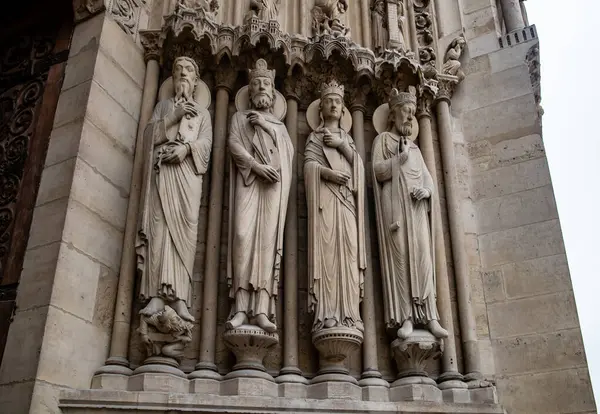 Paris, Fransa-Nisan 16, 2025: Azizlerin ve kralların tam vücut gotik heykelleri katedral kapısının önünde duruyor, kutsal ve kraliyet figürlerini taşla temsil ediyorlar..