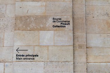 Paris, Fransa-14 Nisan 2025: Bourse de Commerce 'in taş duvarına basılmış bir yön işareti ziyaretçileri ana girişe doğru yönlendiriyor.