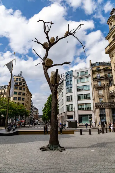 Paris, Fransa-14 Nisan 2025: Giuseppe Penone 'nin bronz heykeli Idee de Pierre, Paris plazasında dallarında büyük taşlar tutan yapraksız bir ağacı gösteriyor..