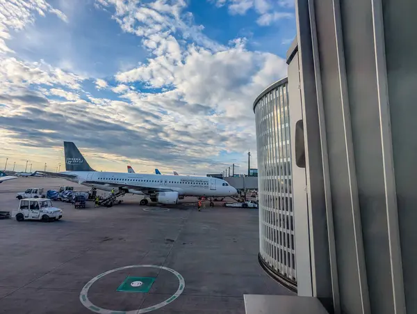 Almanya, Berlin, BER Havaalanı - 13 Nisan 2025: Yer mürettebatı, gün batımında, yakınlarda bagaj ve kargo arabalarıyla birlikte, asfalt üzerinde Nesma Airlines uçakları ile ilgilenmektedir..