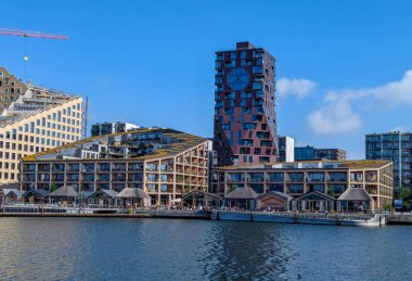 Aarhus, Danimarka-15 Ağustos 2025: Modern binalar, ahşap cepheleri, açık hava restoranları ve büyük saatli benzersiz kırmızı kulesi olan liman bölgesi.