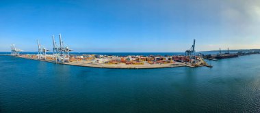 Aarhus, Danimarka-15 Ağustos 2025: Kargo gemileri, vinçler ve kıyı şeridi boyunca güneşli mavi gökyüzü altında çok renkli konteynırlar bulunan konteyner limanının geniş görünümü.