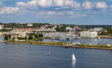 Kiel, Almanya-09.08.2025: Askeri gemiler deniz üssüne kentli binalar ve yeşilliklerle çevrili yelkenli tekneleriyle kenetlendi.