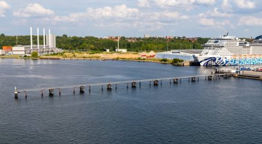 Kiel, Almanya-09.08.2025: MSC Euribia yolcu gemisi, arka planda uzun rıhtım ve sanayi tesisleri bulunan terminalin yanına yanaştı.