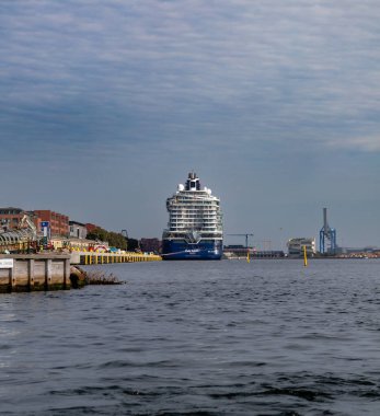 Kopenhag, Danimarka-14 Ağustos 2025: Endüstriyel binalar ve liman altyapısı ile çevrili büyük modern yolcu gemisi.