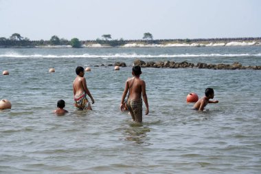 Jakarta, Indonesia on May 20,2024: Asian children are swimming at the edge of Ancol beach. defocused