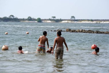 Jakarta, Indonesia on May 20,2024: Asian children are swimming at the edge of Ancol beach. defocused