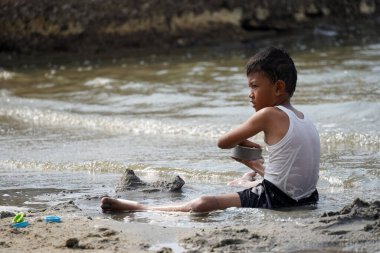 Jakarta, Indonesia on May 20,2024 : Asian children are playing in the sand on the edge of Ancol beach. defocused