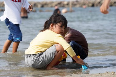 Jakarta, Indonesia on May 20,2024: Asian children are playing in the sand on the edge of Ancol beach. defocused