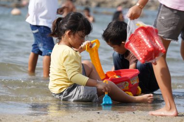 Jakarta, Indonesia on May 20,2024: Asian children are playing in the sand on the edge of Ancol beach. defocused