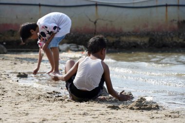 Jakarta, Indonesia on May 20,2024: Asian children are playing in the sand on the edge of Ancol beach. defocused