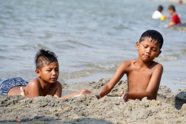 Jakarta, Indonesia on May 20,2024: Asian children are playing in the sand on the edge of Ancol beach. defocused