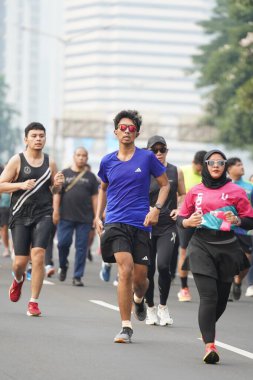 9 Haziran 2024 'te Endonezya' nın Jakarta kenti: Sudirman - Thamrin, Merkez Jakarta 'da sabah saatlerinde Arabasız Günü' nde egzersiz yapan Asyalı insanlar. Seçici odaklanma. Odaklanamadı