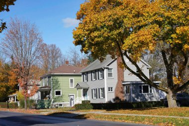 Suburban residential street with bright fall colors and middle class houses with aluminum siding clipart