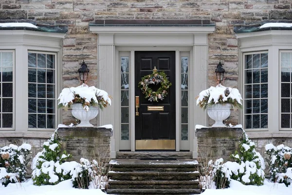 Front door of stone house in winter with Christmas decoration