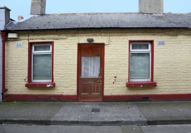 Küçük bir tuğla ev, tuğlalar sarıya boyanmış.