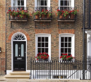 Londra 'daki eski tuğla konak. Pencere kutularında sardunyalar var.