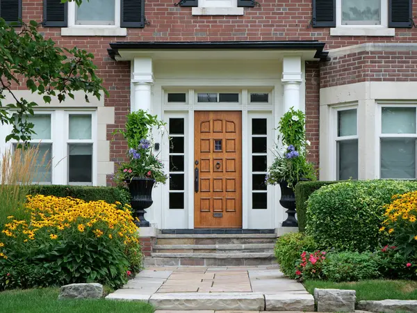 Zarif ahşap ön kapı yazın çiçeklerle çevrili.