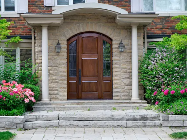 Zarif ahşap ön kapı çiçeklerle çevrili.