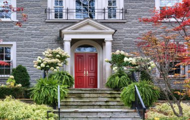 Portico girişi ve kestane rengi çift kapılı taş ev.