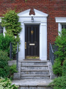 Sarmaşıklı tuğla ev ve parlak kırmızı ön kapı.