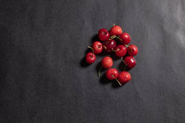 Siyah arka plana serpilmiş tatlı kırmızı kirazlar. Üst Manzara. Meyve Arkaplanı.