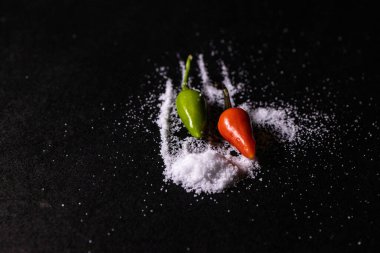 Siyah arka planda tuz bulunan kırmızı ve yeşil biberler. Kapatın. Seçici odaklanma. Yemek fotoğrafçılığı. Makro Fotoğraf.