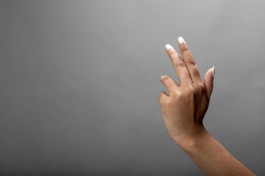 Gri arkaplanda farklı ifade ya da duygu gösteren kadın eli.