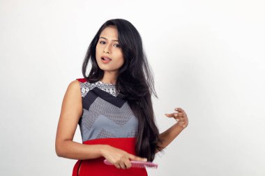 Gri arka planda kırmızı ve gri renkli ve mavi kot pantolon giyen, gündelik giyimli genç ve güzel bir Hintli kadın modelin stüdyo fotoğrafı. Kadın manken. Moda Portresi.