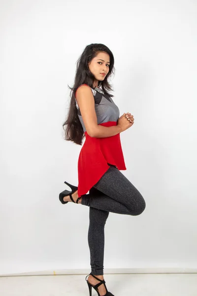白い背景に赤と灰色のデザイナーの上と黒のジーンズを身に着けているカジュアルな着用で 若く美しいインドの女性モデルのスタジオ撮影 女性モデル ファッション ポートレイト — ストック写真