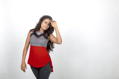 Genç, güzel bir Hintli kadın modelin gündelik kıyafetleriyle stüdyo fotoğrafı. Kırmızı ve gri tasarımcı bluzu ve beyaz arka planda siyah kot pantolon giyiyor. Kadın manken. Moda Portresi.