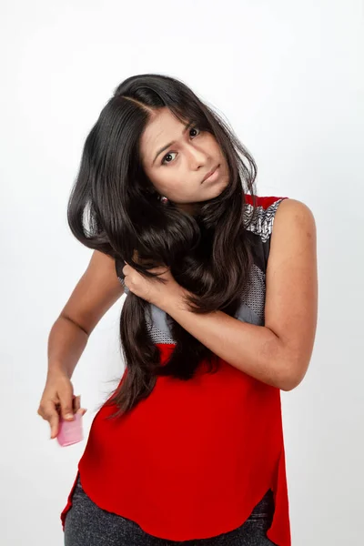 白い背景に赤と灰色のデザイナーのトップと黒のジーンズを身に着けているカジュアルな髪を着た若いインドの女性モデル 広告ショット — ストック写真