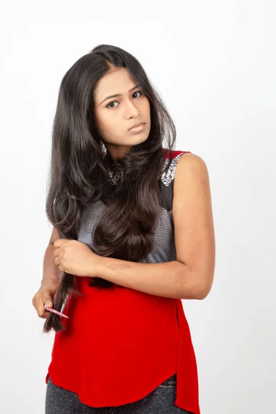 白い背景に赤と灰色のデザイナーのトップと黒のジーンズを身に着けているカジュアルな髪を着た若いインドの女性モデル 広告ショット — ストック写真