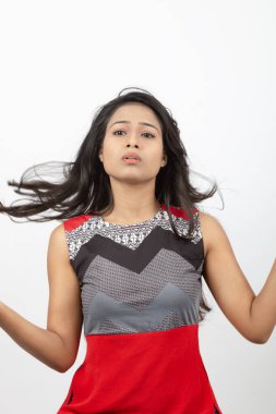 Genç, güzel bir Hintli kadın modelin gündelik kıyafetleriyle stüdyo fotoğrafı. Kırmızı ve gri tasarımcı bluzu ve beyaz arka planda siyah kot pantolon giyiyor. Kadın manken. Moda Portresi.