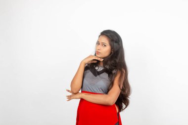 Genç, güzel bir Hintli kadın modelin gündelik kıyafetleriyle stüdyo fotoğrafı. Kırmızı ve gri tasarımcı bluzu ve beyaz arka planda siyah kot pantolon giyiyor. Kadın manken. Moda Portresi.
