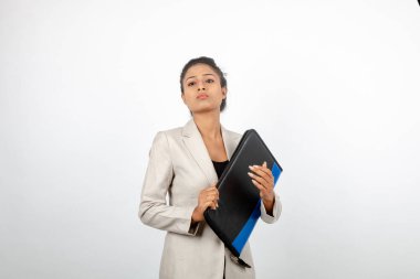 Ofisteki kadın bir dosya tutuyor ve sunum yapıyor. Resmi giyinmiş genç bir kadın beyaz arka planda beyaz ceket giyiyor..