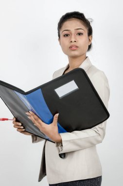 Ofisteki kadın elinde bir dosya, kalem ve sunum tutuyor. Resmi giyinmiş genç bir kadın beyaz arka planda beyaz ceket giyiyor..