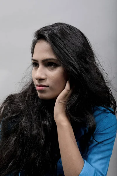 Indian female young model in blue casual shirt against grey background - stock photo. Long black hair model wearing blue shirt.